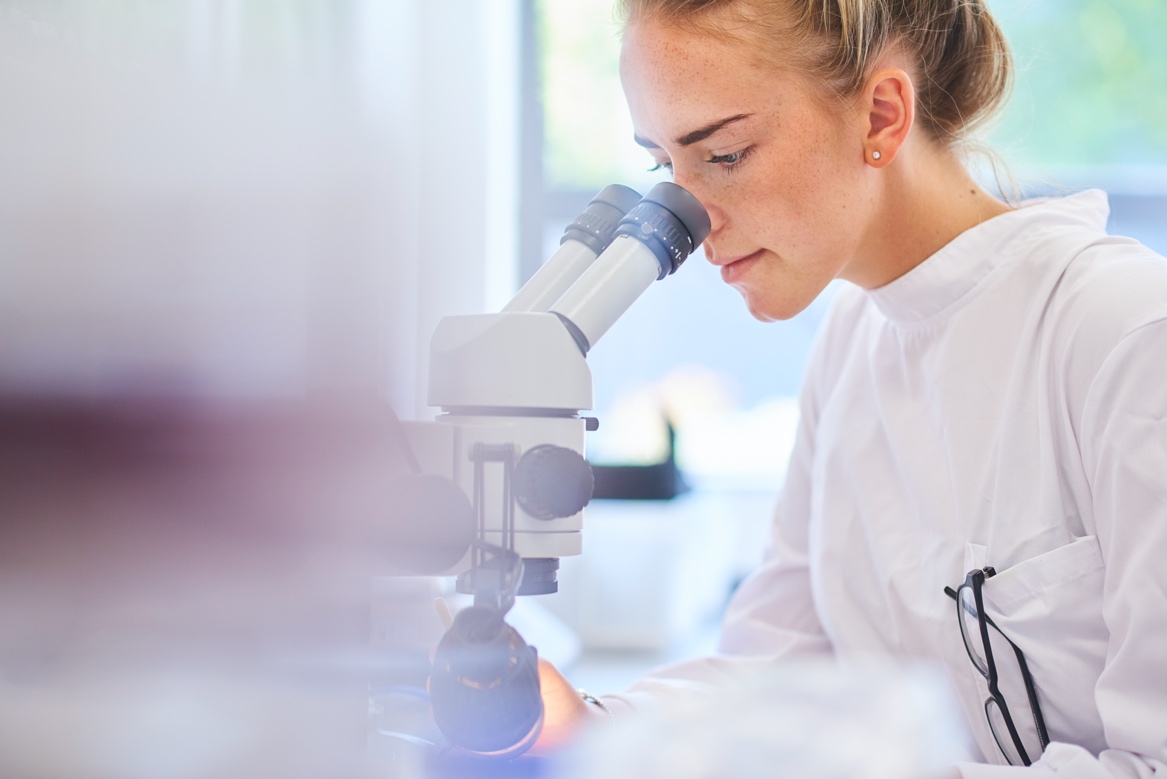 A person looking through a microscope

Description automatically generated with medium confidence